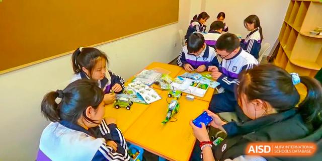 Students working on a creative project with small tools and materials around a table at Shenyang Feiyue Experimental School.