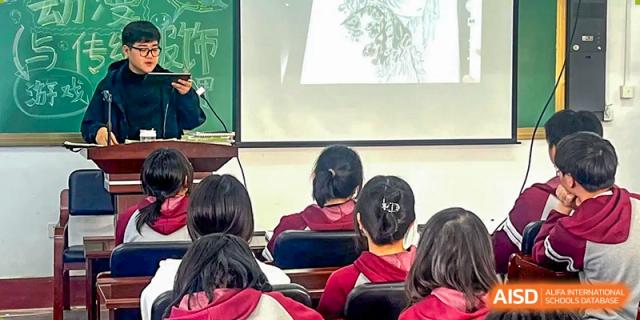 Students watching a presentation or video on a large screen in a classroom or hall at Shenyang Feiyue Experimental School.