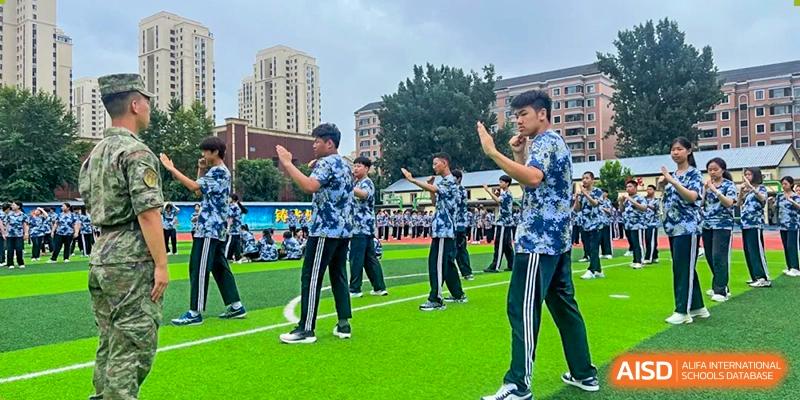 Students performing a synchronized martial arts or exercise routine outdoors at Shenyang Feiyue Experimental School.