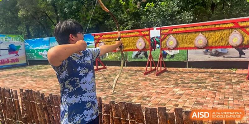 A student aiming a bow and arrow at a target during an archery practice at Shenyang Feiyue Experimental School.