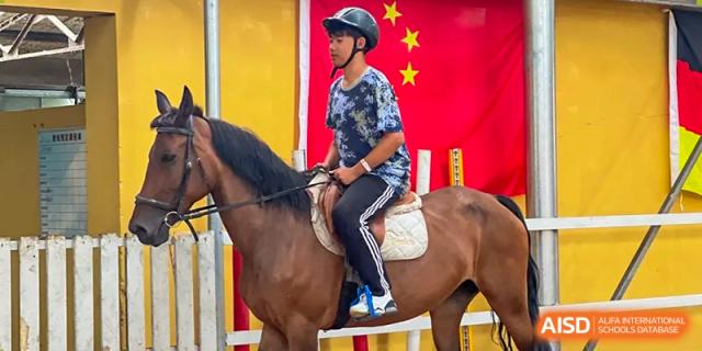 A student wearing a helmet and riding a horse during a school activity or demonstration at Shenyang Feiyue Experimental School.