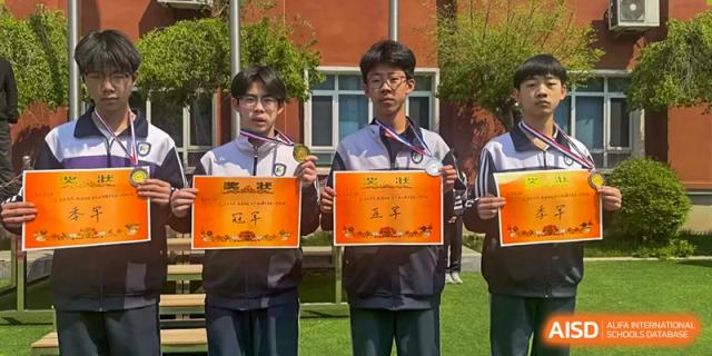 Two male students standing outside, proudly displaying their medals and achievement certificates at Shenyang Feiyue Experimental School.