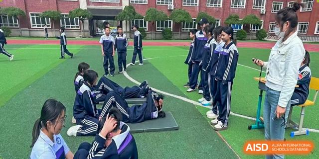 Students resting or stretching on the green sports field at Shenyang Feiyue Experimental School.
