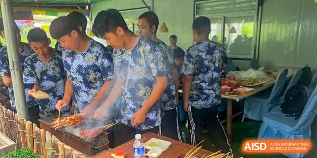 Students grilling food at a barbecue or outdoor cooking event at Shenyang Feiyue Experimental School.