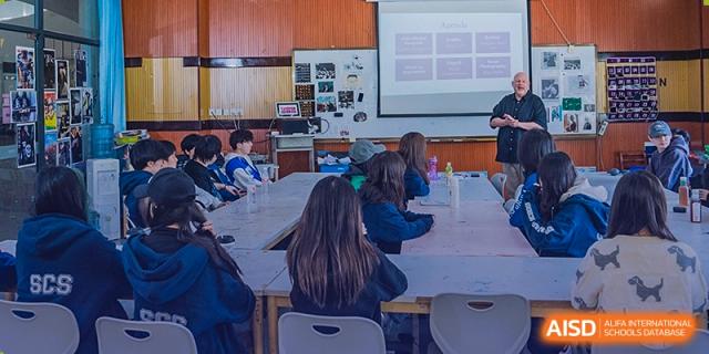 Students seated at desks in a classroom, listening to a presentation at Sino-Canada School.