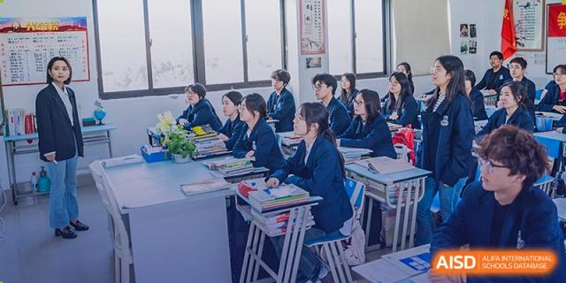 Students in school uniforms are sitting in a classroom with textbooks on their desks at Sino-Canada School.