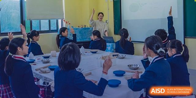 A teacher from Sino-Canada School standing in front of a classroom, instructing a group of students during a lesson.