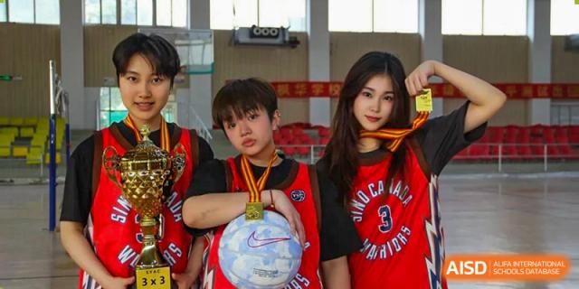 Two students wearing basketball jerseys and gold medals, posing for a photo at Sino-Canada School.