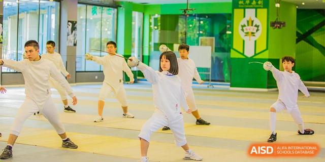 A student in a white uniform holding a foil, practicing fencing at Sino-Canada School.