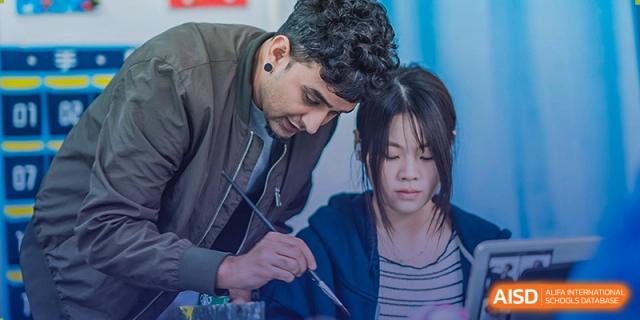 Two students, a male and a female, are sitting together and painting at Sino-Canada School.