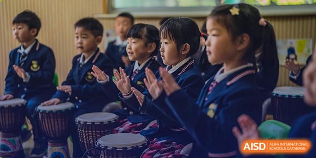 Students clapping and playing drums in a music class at Sino-Canada School.