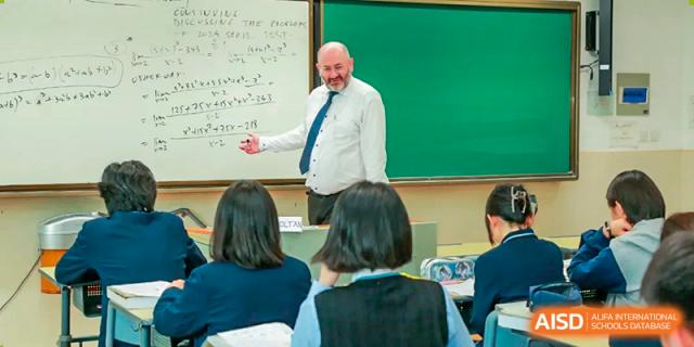 A male teacher from Suzhou Experimental High School International Center writes on a chalkboard for his students.
