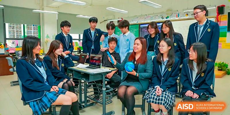 Students and a female teacher from Suzhou Experimental High School International Center sit at a desk with a laptop.