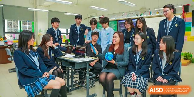 A group of students from Suzhou Experimental High School International Center and a teacher sit at a desk with a laptop.