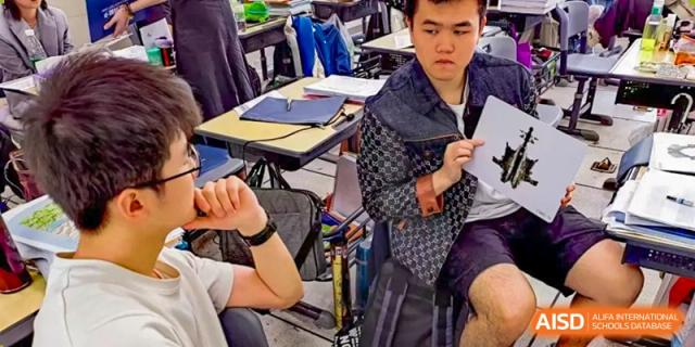 A male student from Suzhou Experimental High School International Center in a patterned jacket sits at his desk.