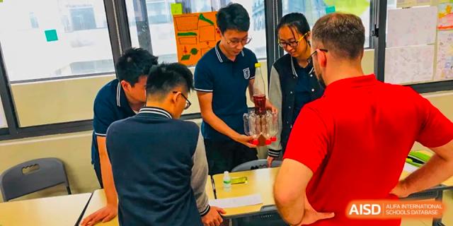 A male student from Suzhou Experimental High School International Center helps to pour liquid from a beaker.