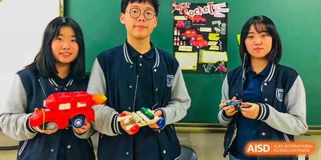 A male student from Suzhou Experimental High School International Center in a dark jacket holds a small device.