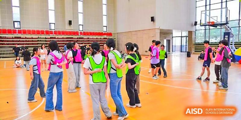 A group of students from Suzhou Experimental High School International Center in bright green vests stand in a gym.