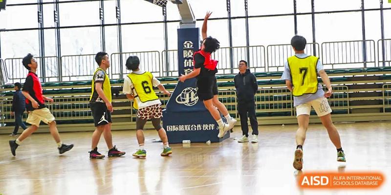 A basketball player from Suzhou Experimental High School International Center wearing a black and red uniform jumps high to shoot the ball.