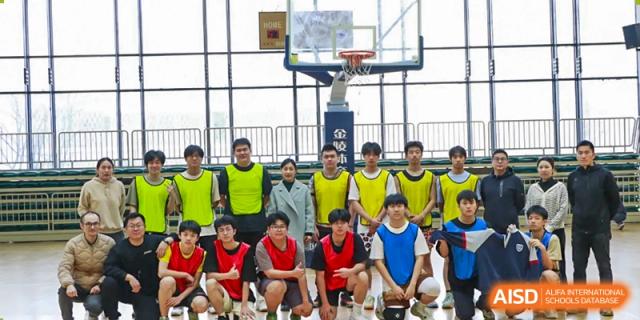 A group of male students from Suzhou Experimental High School International Center, some wearing yellow vests, pose for a group photo on a basketball court.