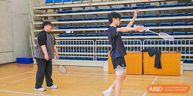 A student from Suzhou Experimental High School International Center in a black T-shirt and shorts stretches on a basketball court.