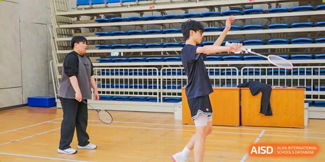 A student from Suzhou Experimental High School International Center in a black T-shirt and shorts stretches on a basketball court.