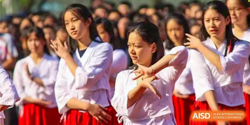 A female student from Suzhou Experimental High School International Center in a white and red uniform performs a dance.
