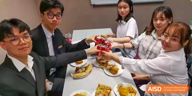 Students from Suzhou Experimental High School International Center raise red soda cans to toast a meal.