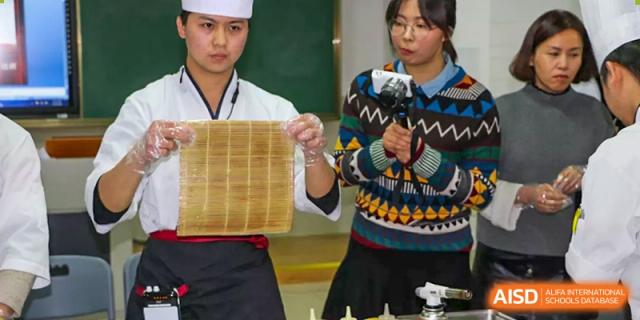 A student from Suzhou Experimental High School International Center holds a bamboo mat and is being filmed.