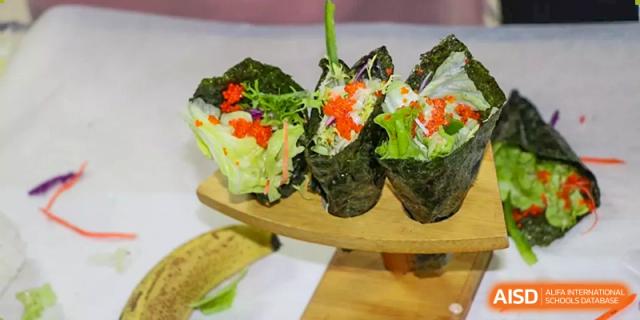 Fresh spring rolls wrapped in seaweed, topped with red roe, and served on a wooden platter Suzhou Experimental High School International Center.