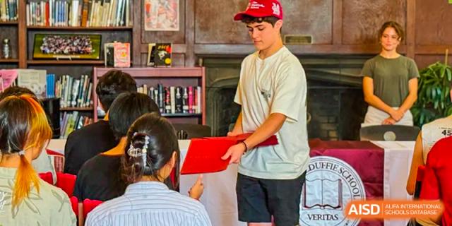 A male student is receiving an award from a teacher at The MacDuffie School Tianjin.