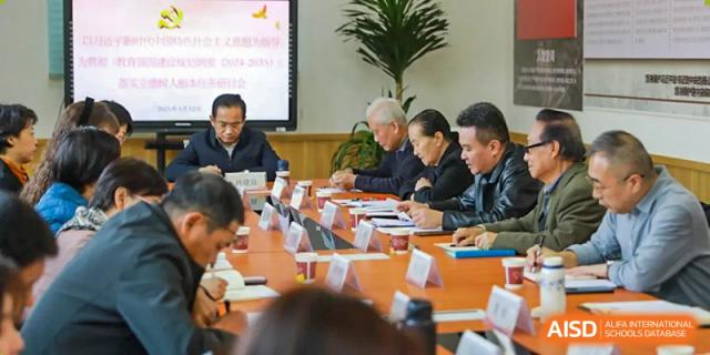 A group of male and female staff are sitting around a conference table in a meeting room at The MacDuffie School Tianjin.