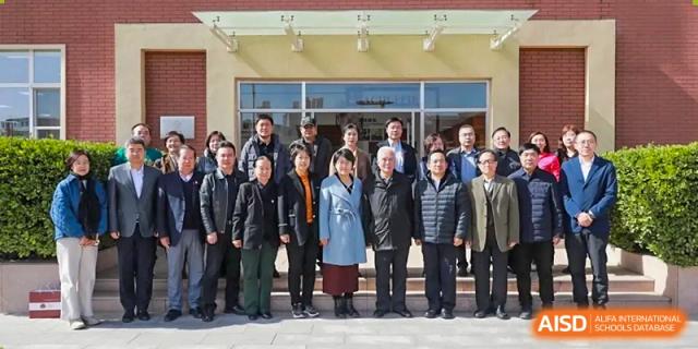 A group of male and female students and staff are posing for a group photo outside a building at The MacDuffie School Tianjin.