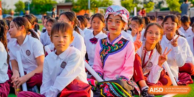 A group of female students in traditional folk attire are posing for a photo at The MacDuffie School Tianjin.