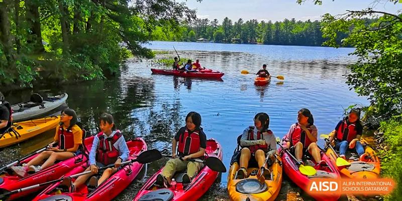 Students from The MacDuffie School Tianjin are kayaking on a lake during an outdoor trip.