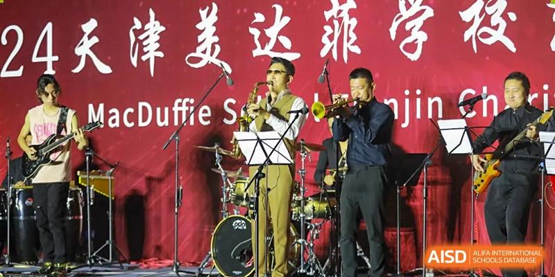 A male student is playing the trumpet as part of a student band on stage at The MacDuffie School Tianjin.
