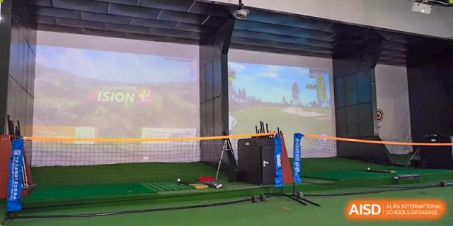 A male student is practicing his golf swing in an indoor golf training facility at The MacDuffie School Tianjin.