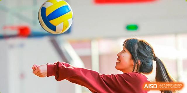A female student is playing volleyball on a sunny day at The MacDuffie School Tianjin.