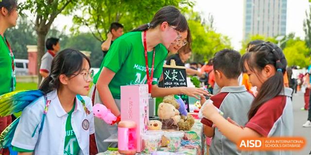 A female student is managing a booth at a school fair or festival at The MacDuffie School Tianjin.