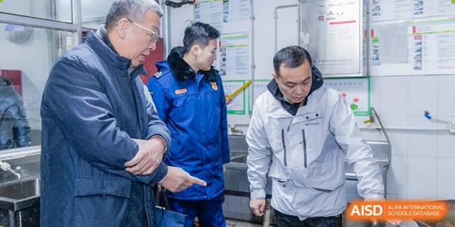 Two male staff members are pointing at something while walking in an alley at The MacDuffie School Tianjin.