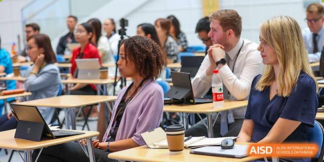 A diverse group of adults and teachers, potentially Wellington College International Hangzhou staff, participating in a professional development session or meeting.