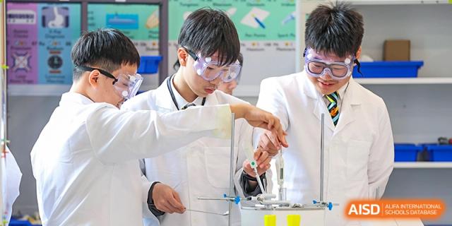 A Wellington College International Hangzhou student wearing a lab coat and safety goggles, conducting a science experiment in a laboratory.