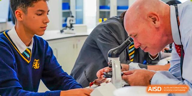 A teacher helping a Wellington College International Hangzhou student use a microscope in a science laboratory.