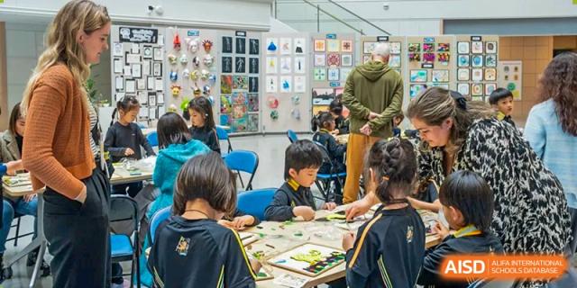 Wellington College International Hangzhou students working together on a collaborative hands-on project in a bright room with visual displays.