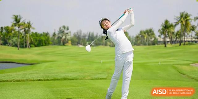 A female student in white golf attire taking a swing on a sunny golf course. Wellington College International Hangzhou