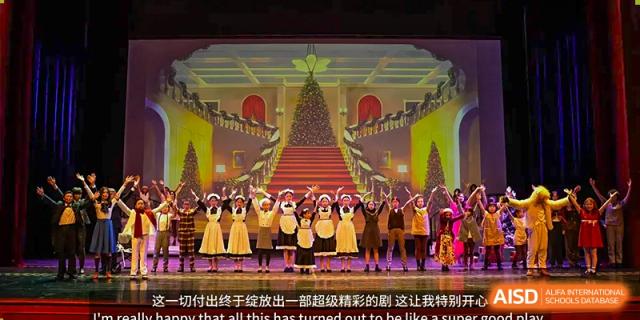 Students in black and white maid-like costumes standing on a grand staircase decorated for a Christmas performance or gala. Wellington College International Hangzhou