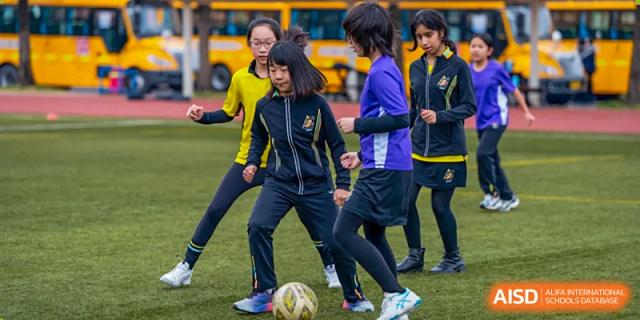 Wellington College International Hangzhou students playing soccer on a field, focused on kicking the ball during a game or practice.