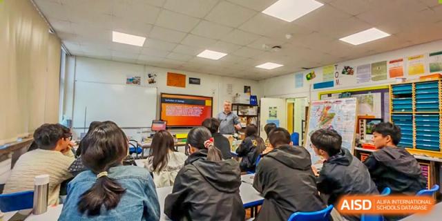 Zhejiang Wenzhou High School International Division students participating in a classroom discussion, focusing on a presentation visible on a large screen.