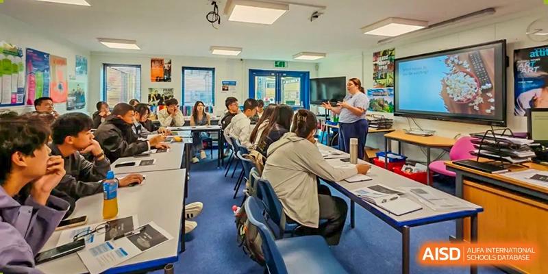 A classroom setting at Zhejiang Wenzhou High School International Division with students seated around tables, engaged in a lesson led by a teacher.