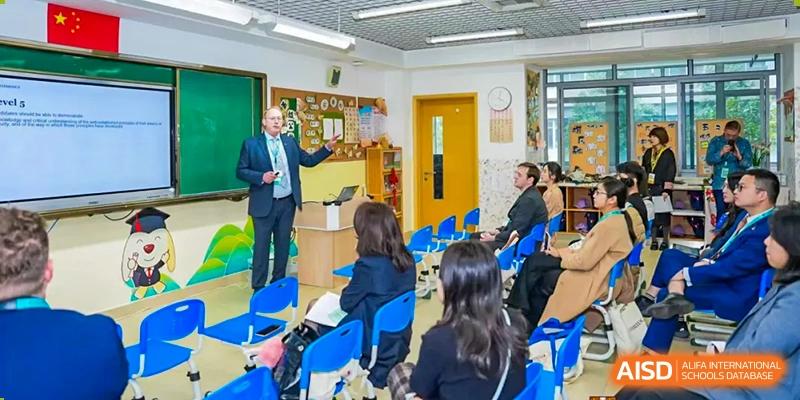 A teacher giving a presentation to a small class of younger students in a bright classroom at Zhejiang Wenzhou High School International Division.